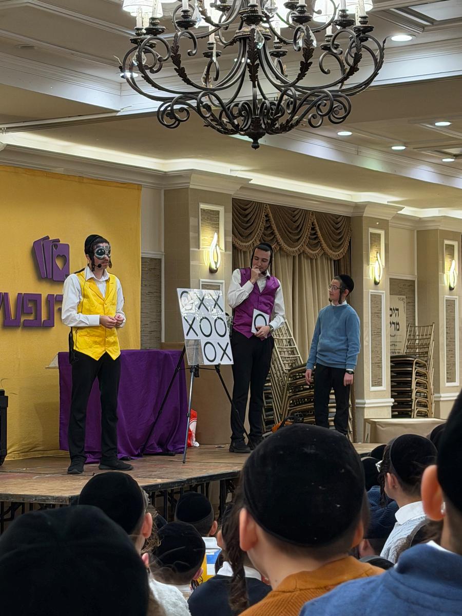 Mechy and Shloimy on stage in a ballroom, in their yellow and purple vests